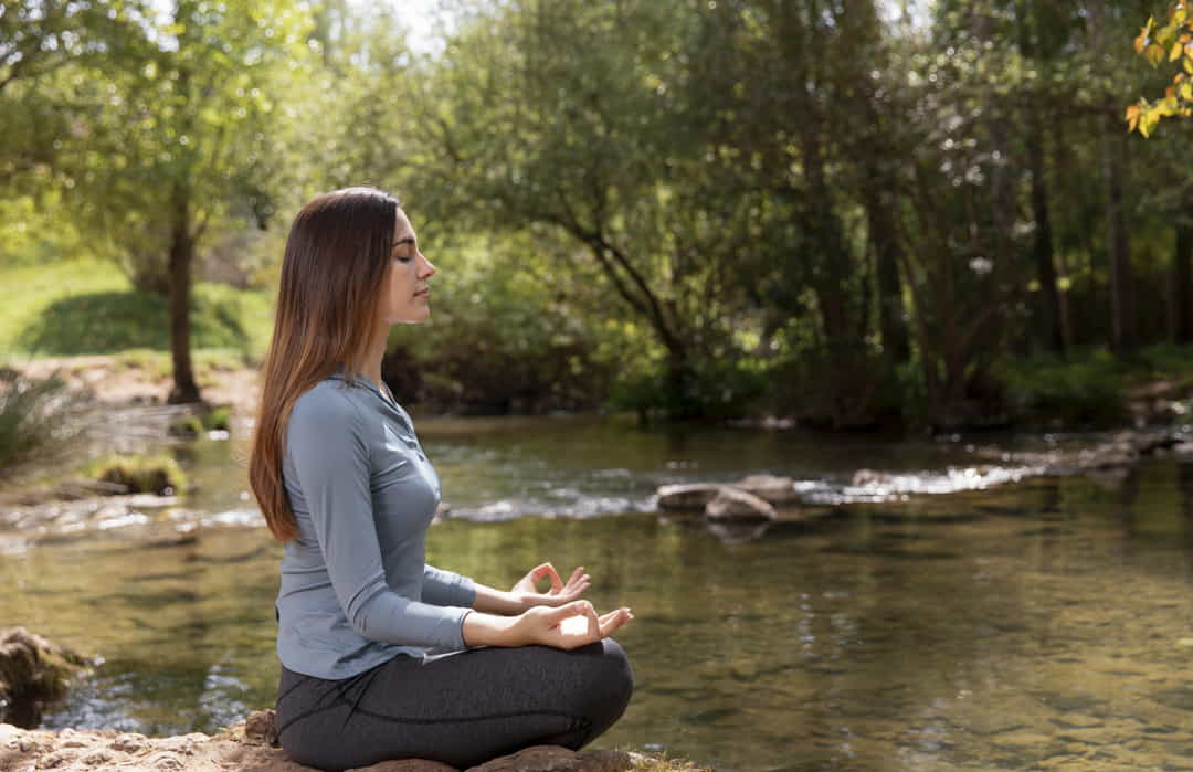 Mujer meditando en la naturaleza para obtener autoconocimiento